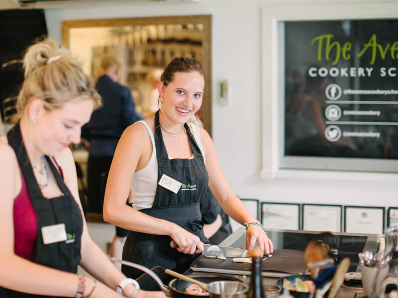 Two women wearing aprons at a cooking class